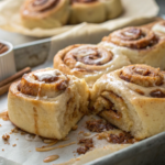 A stack of freshly baked vegan sourdough cinnamon rolls with gooey cinnamon filling and creamy maple glaze, served on a rustic wooden board.